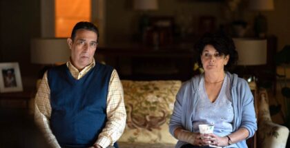 Ciaran Hinds and Roisin Gallagher sit on a sofa