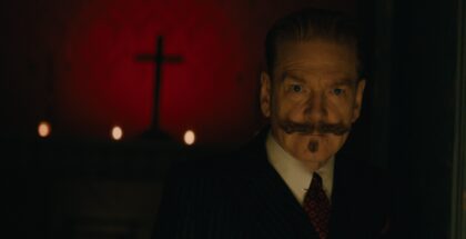 Kenneth Branagh's Hercule Poirot looks sternly ahead with a red background and a cross behind him